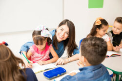 Erzieherin, die ihren Job genießt und Schüler in einem Klassenzimmer unterrichtet